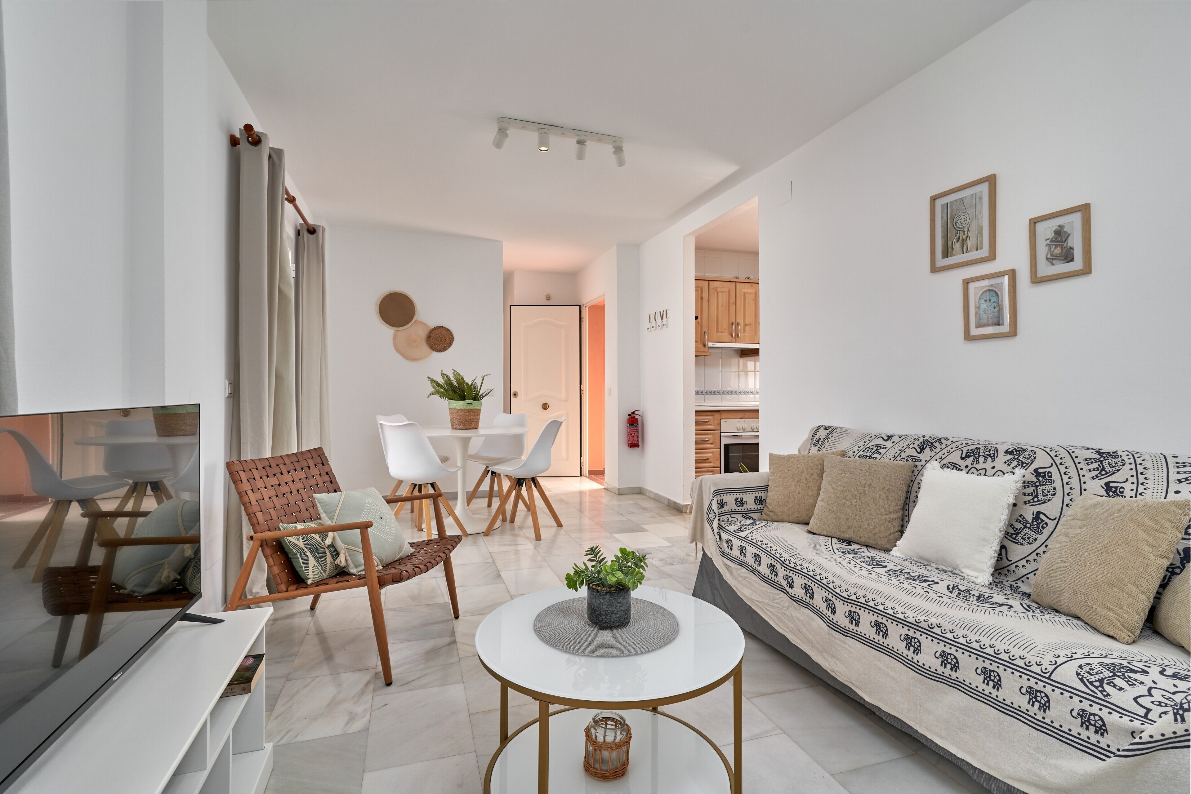 A modern living room with a sofa, TV, coffee table, and a dining area with chairs and a table.