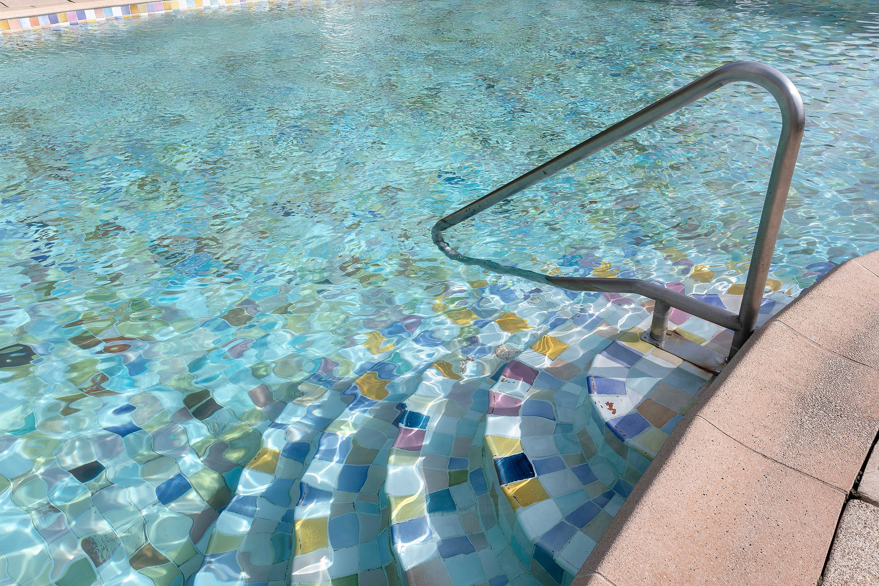 A swimming pool with a tiled edge and a metal ladder.