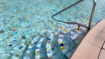 A swimming pool with a tiled edge and a metal ladder.
