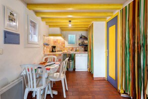 A kitchen with a dining area, white chairs, a table, and a colorful curtain. - House "Great Location, Pool, Dogs Welcome, Garden" with Shared Pool, Private Terrace & Wi-Fi (Lorgues)
