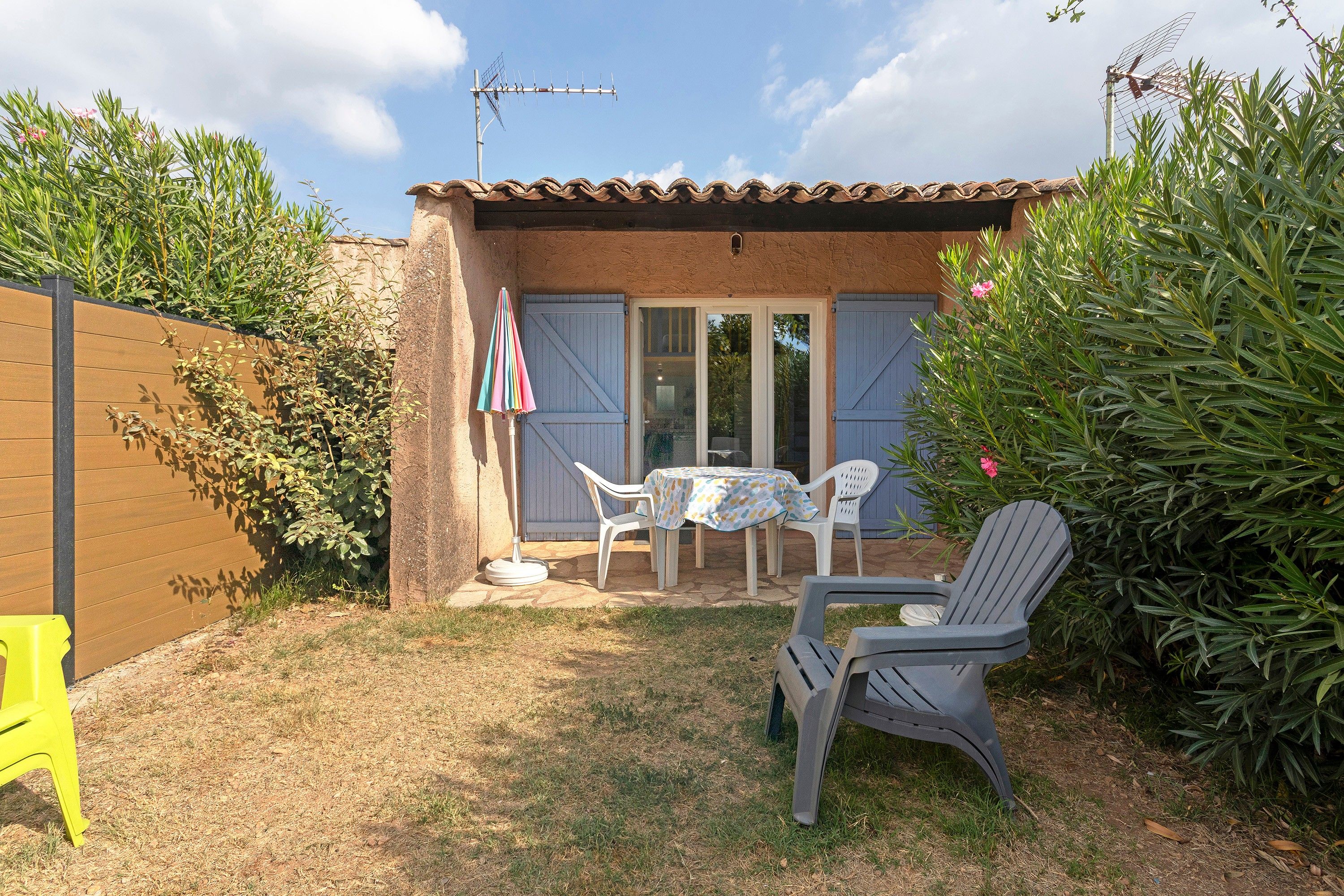A patio with a table and chairs, a small covered seating area, and a garden with a fence.