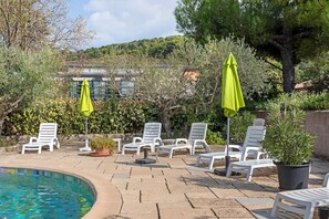 A poolside area with lounge chairs and umbrellas, surrounded by greenery and a building in the background. - House "Great Location, Pool, Dogs Welcome, Garden" with Shared Pool, Private Terrace & Wi-Fi (Lorgues)