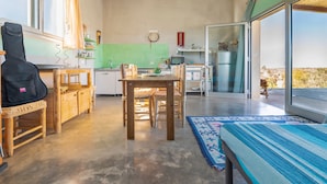 A compact kitchen with a dining area, a guitar, and a large sliding glass door leading to a balcony. - Villa "Casa Romantica" with Shared Pool, 2 Private Terraces & Wi-Fi (Otranto)