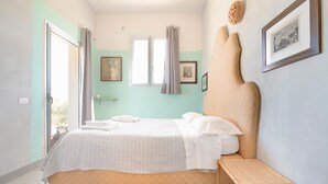 A bedroom with a bed, a bedside table, a window with curtains, and a wall-mounted picture. - Villa "Casa Romantica" with Shared Pool, 2 Private Terraces & Wi-Fi (Otranto)