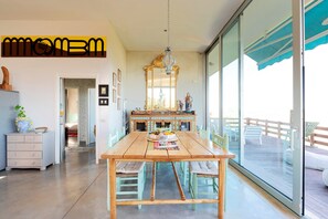 A dining area with a wooden table, chairs, a chandelier, and a large mirror.