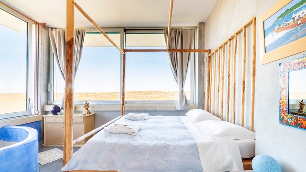 A room with a bed, a large window, a wooden frame, a blue bathtub, and a wall with a framed picture. - Deluxe Double Room B&B Villa with Shared Pool, Private Terrace and Wi-Fi (Otranto)