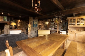 Un intérieur rustique avec une cheminée en pierre, des meubles en bois, une bibliothèque et un buffet en bois.