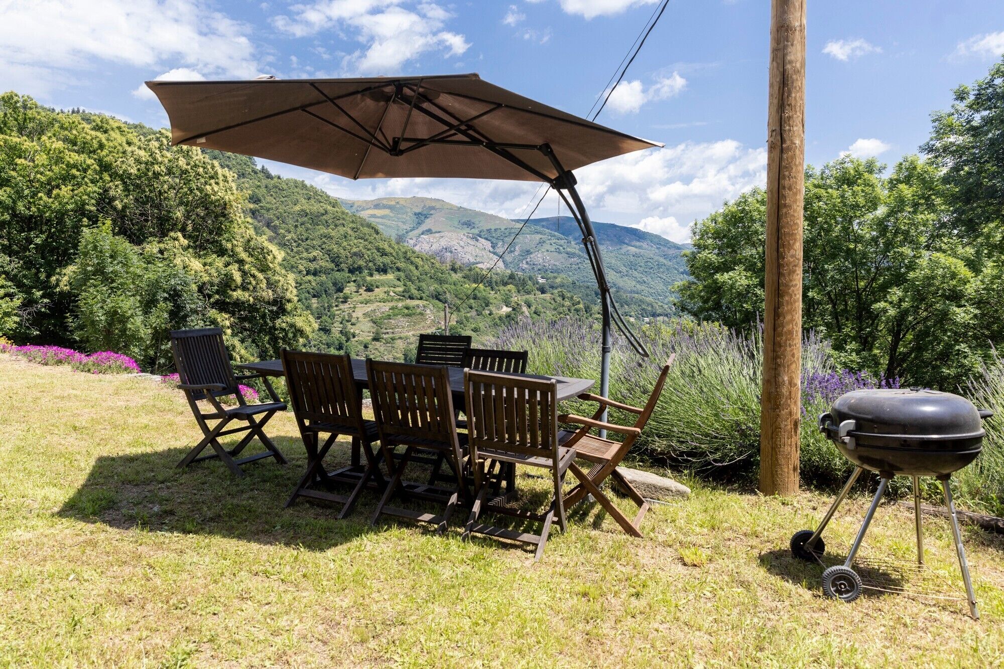 Un espace extérieur aménagé pour les repas, avec une table et des chaises, un barbecue et une vue sur un paysage montagneux.