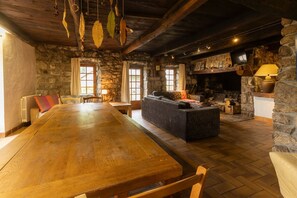 Un intérieur rustique avec une table en bois, des murs en pierre, une cheminée et un canapé.