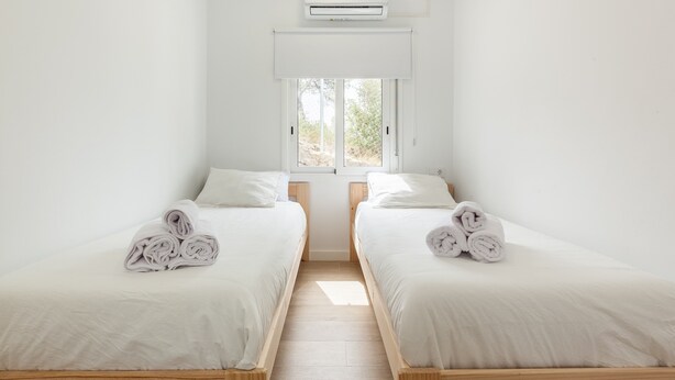 A room with two beds, a window, and an air conditioning unit. - Holiday Home "Casita Palmeras" with Mountain Views, Private Garden and Wi-Fi (Canyelles)