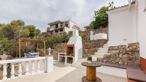 A patio with a wooden table, a barbecue area, and a white railing. - Holiday Home "Casita Palmeras" with Mountain Views, Private Garden and Wi-Fi (Canyelles)