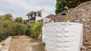 A modern building with a stone wall and a white, textured structure in the foreground. - Holiday Home "Casita Palmeras" with Mountain Views, Private Garden and Wi-Fi (Canyelles)