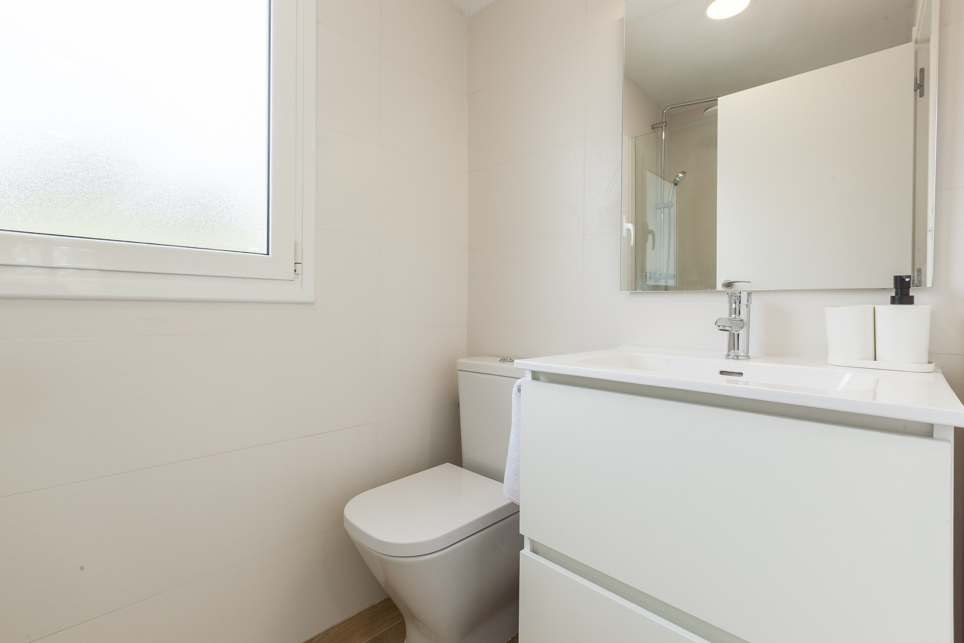 Ein Badezimmer mit Toilette, Waschbecken, Spiegel und Fenster.