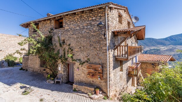 A stone building with a balcony, a door, and a small garden area. - Holiday Home "Cal Barral" with Mountain View, Balcony & Wi-Fi (Ansovell)