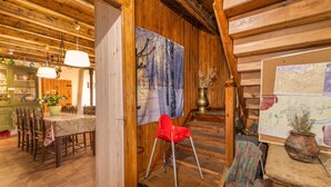 A wooden interior with a dining area, a red chair, a map, and a vase with dried plants. - Holiday Home "Cal Barral" with Mountain View, Balcony & Wi-Fi (Ansovell)