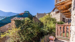 A stone building with a wooden balcony, a stone wall, and a view of mountains. - Holiday Home "Cal Barral" with Mountain View, Balcony & Wi-Fi (Ansovell)