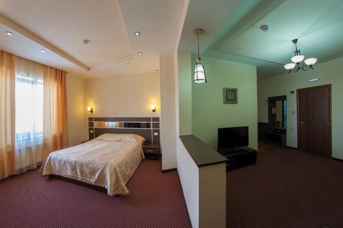 Habitació d'hotel amb un llit, un escriptori, una televisió i una porta.