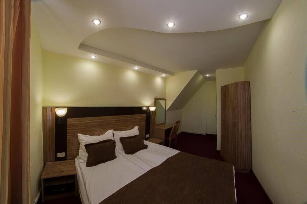 Habitació d'hotel amb llit, taules de nit, un mirall i unes escales.