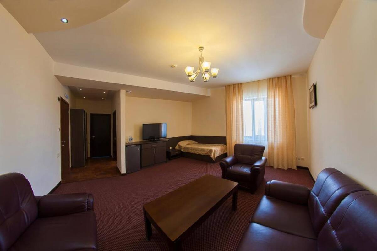 Habitació d'hotel amb seients de sofà, televisió, llit i escriptori.