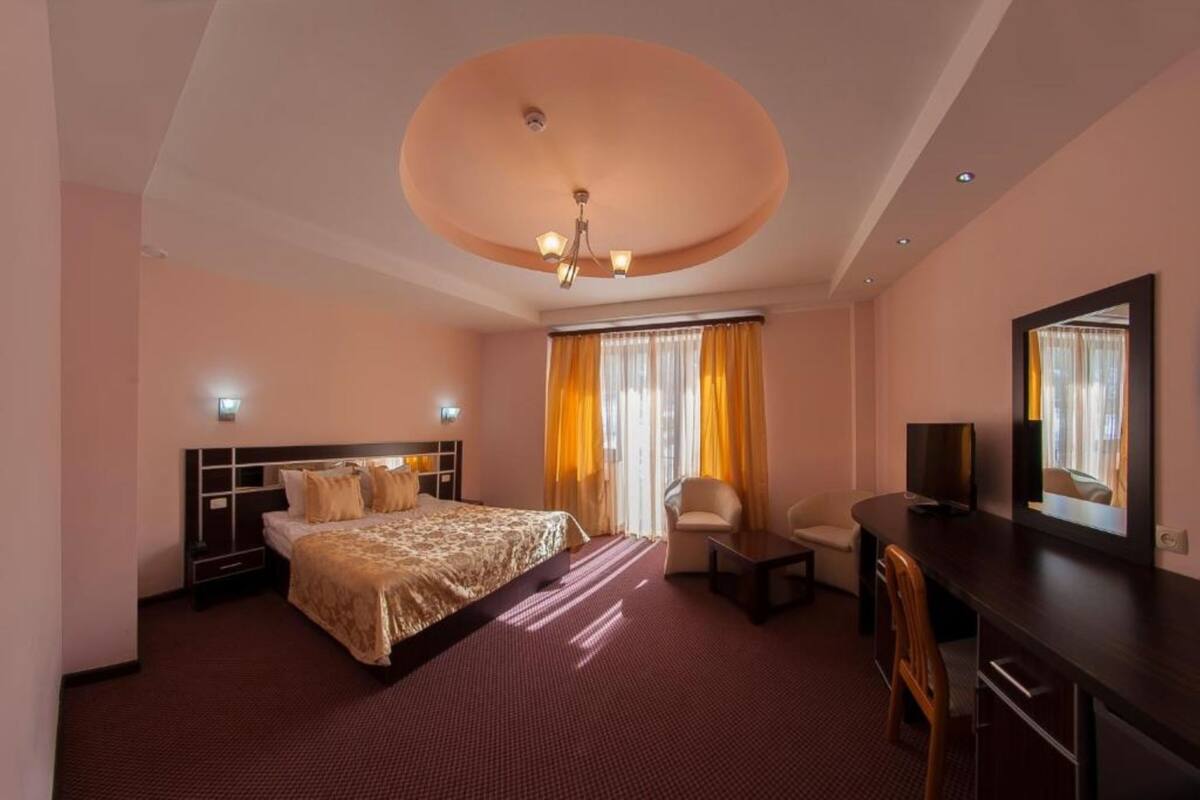 Habitació d'hotel amb un llit gran, escriptori, cadira, televisió i mirall.