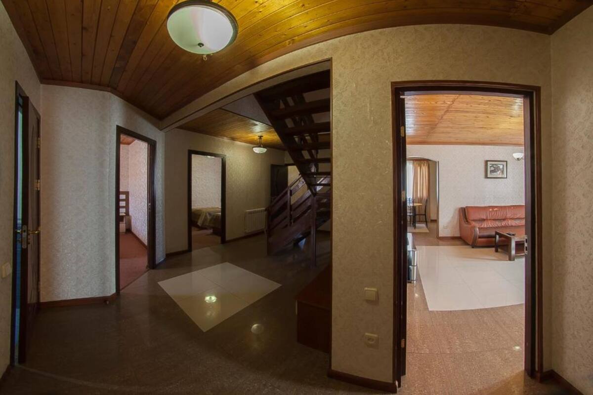 Un passadís espaiós amb sostre de fusta, una escala i una zona de sala d'estar amb un sofà de pell.
