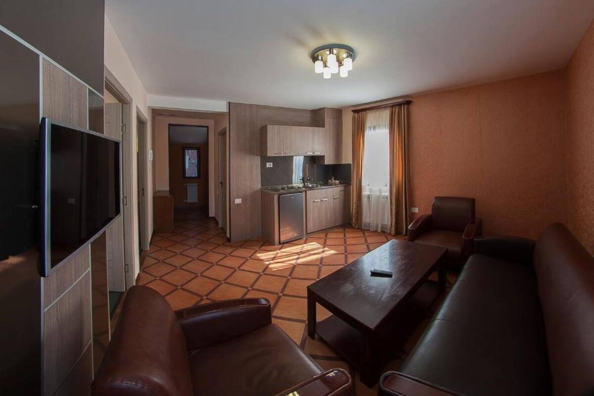 Un espai habitable compacte amb zona de cuina, televisió de pantalla plana, seients de cuir i taula de dinar.