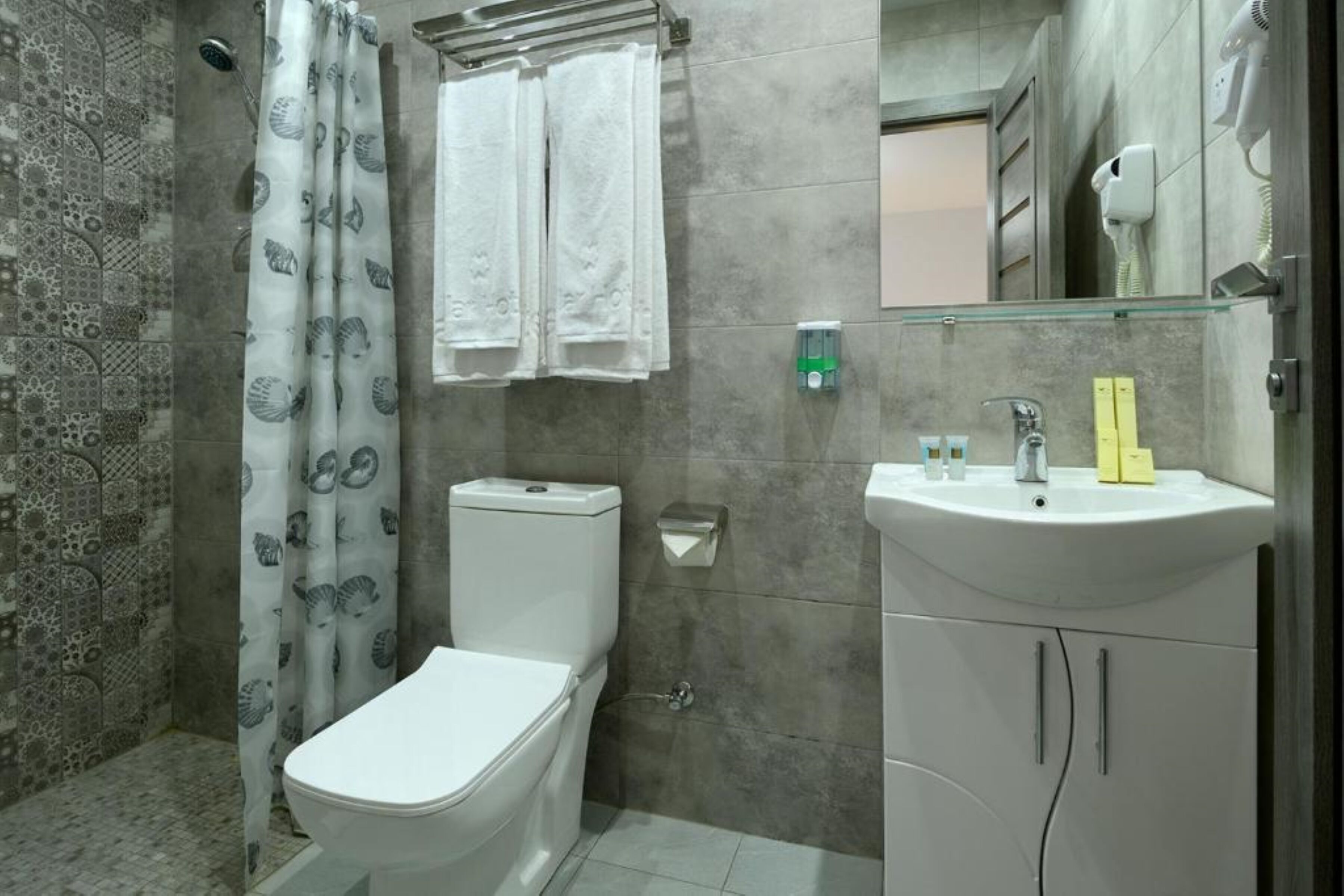 A bathroom with a toilet, shower curtain, towel rack, sink, and a mirror.