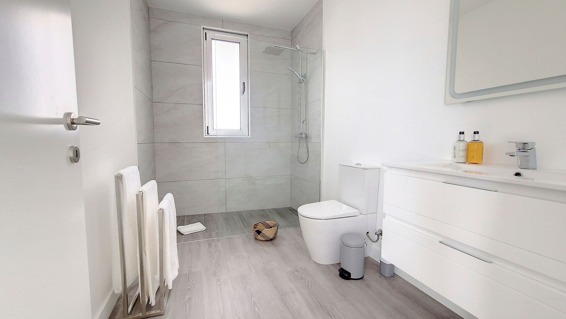 A modern bathroom with a shower, toilet, and white cabinetry.