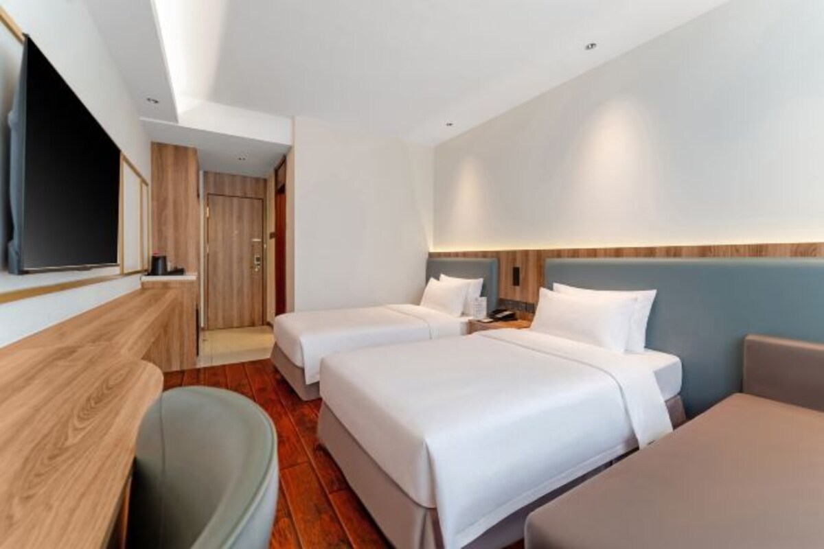 Una camera d'albergo con due letti, una TV, una scrivania e una sedia.