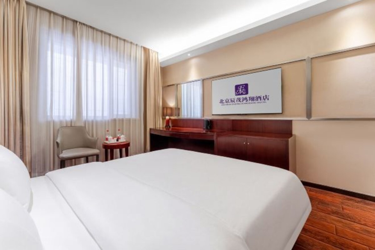 Una camera d'albergo con un letto grande, una scrivania, una sedia, un tavolino e una TV montata a parete.