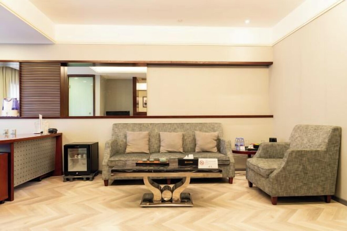 Un salon moderne avec un canapé, un fauteuil et une table basse. On y trouve également un téléviseur et un petit meuble.