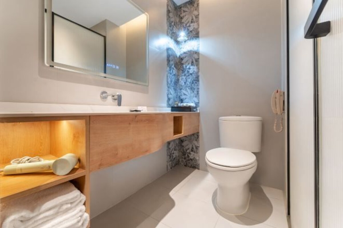 Un bagno moderno con un mobile bagno in legno, un water e uno specchio.