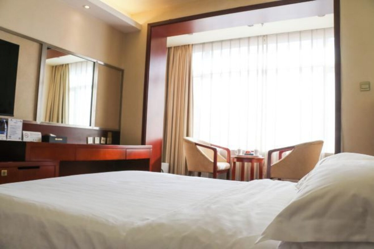 Camera d'albergo con un letto grande, una scrivania, una sedia e una finestra con tende.