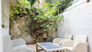 Eine Terrasse mit Korbmöbeln, einem Tisch und einem Blumentopf.
