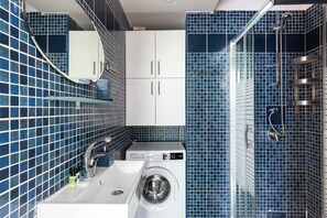 Standaard appartement | Badkamer | Een douche, een haardroger, handdoeken, toiletpapier