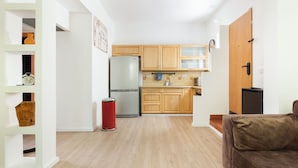 Eine moderne Küche mit Holzschränken, einem Edelstahlkühlschrank und einer roten Mülltonne.
