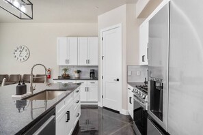 A modern kitchen with white cabinets, a stainless steel refrigerator, a sink, and a clock on the wall. - Sand Hollow Surf! Hang 10 and enjoy some fun in the sun! (Hurricane)