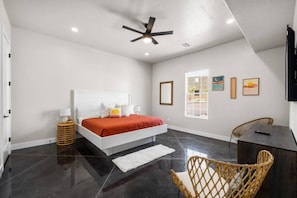 A modern bedroom with a bed, a ceiling fan, a window, and a view of the outdoors.