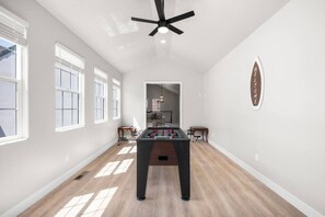 A spacious room with a foosball table, large windows, and a ceiling fan. - Sand Hollow Surf! Hang 10 and enjoy some fun in the sun! (Hurricane)