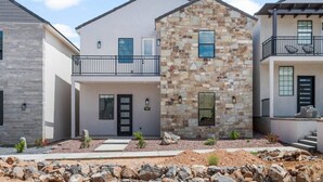 A modern two-story house with a stone facade, a balcony with chairs, and a visible address number.