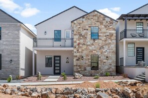 A modern two-story house with a stone facade, a balcony with chairs, and a visible address number. - Sand Hollow Surf! Hang 10 and enjoy some fun in the sun! (Hurricane)
