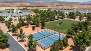 A residential area with houses, a tennis court, and mountains in the background.