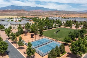 Zona residencial com casas, quadra de tênis e montanhas ao fundo.