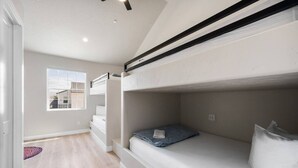 A bedroom with bunk beds, a window, and a view of buildings outside.