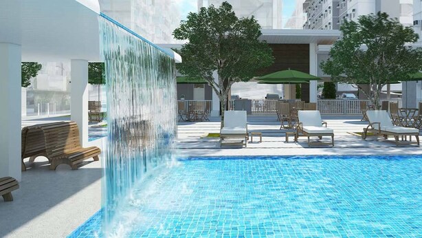 A swimming pool with lounge chairs and a waterfall feature.