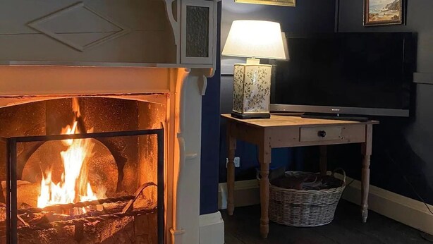 Une pièce chaleureuse avec une cheminée, une lampe et un tableau au mur.