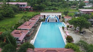 A swimming pool with a slide, surrounded by buildings with red roofs. - Pilot Hotel (Alaminos)