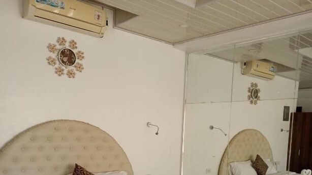 A bedroom with a round bed, a large mirror, and an air conditioning unit on the wall. - Pilot Hotel (Alaminos)