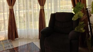 A room with large windows, a dark armchair, and a coffee table. - Pilot Hotel (Alaminos)