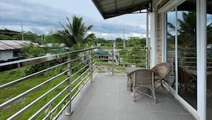A balcony with a metal railing, a wicker chair, and a table. - Pilot Hotel (Alaminos)